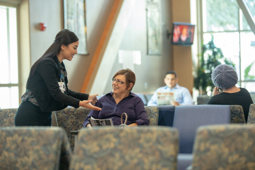 A female Hospital worker is smiling at a female patient in the Hospital Lobby Area